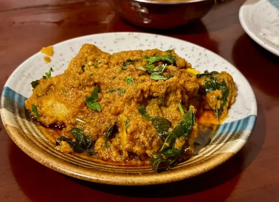 A dish of dry-fried chicken in a dark, spiced masala, garnished with coriander.