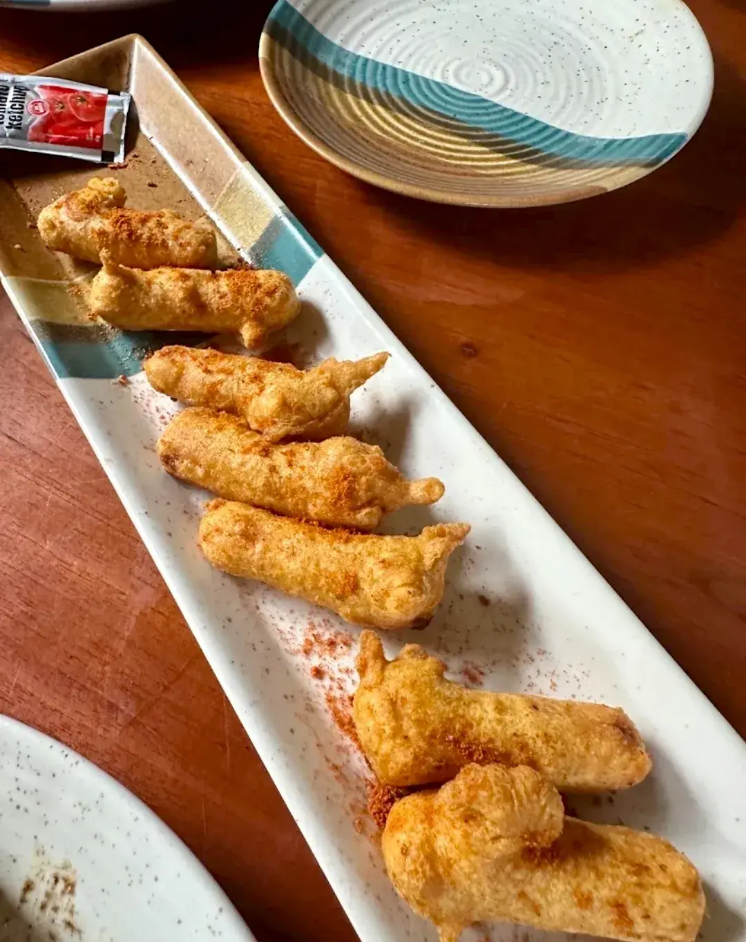 Fried batons arranged along a long rectangular plate.