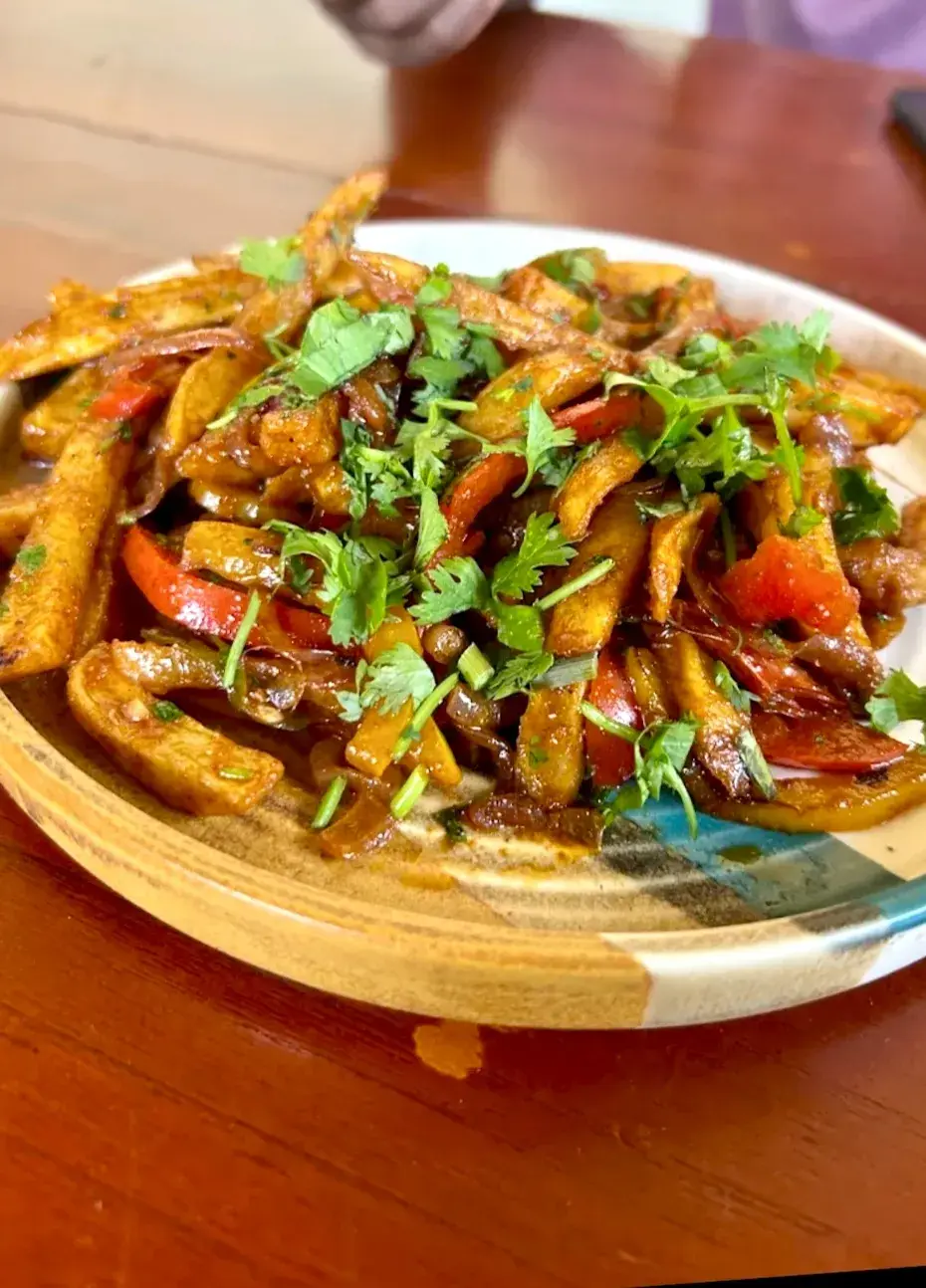 Strips of fried vegetables and peppers piled on a patterned ceramic plate.