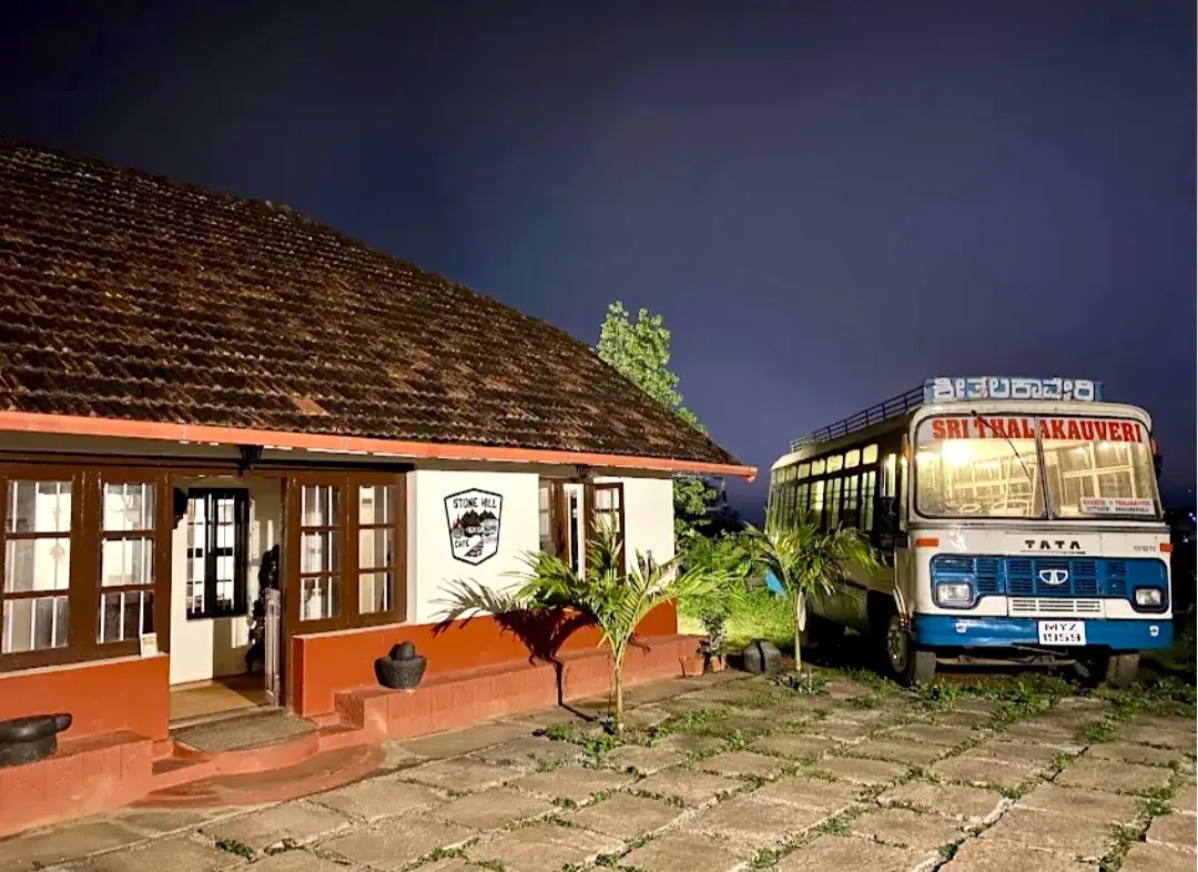 The Stone Hill house at dusk with the blue and white bus parked alongside it.