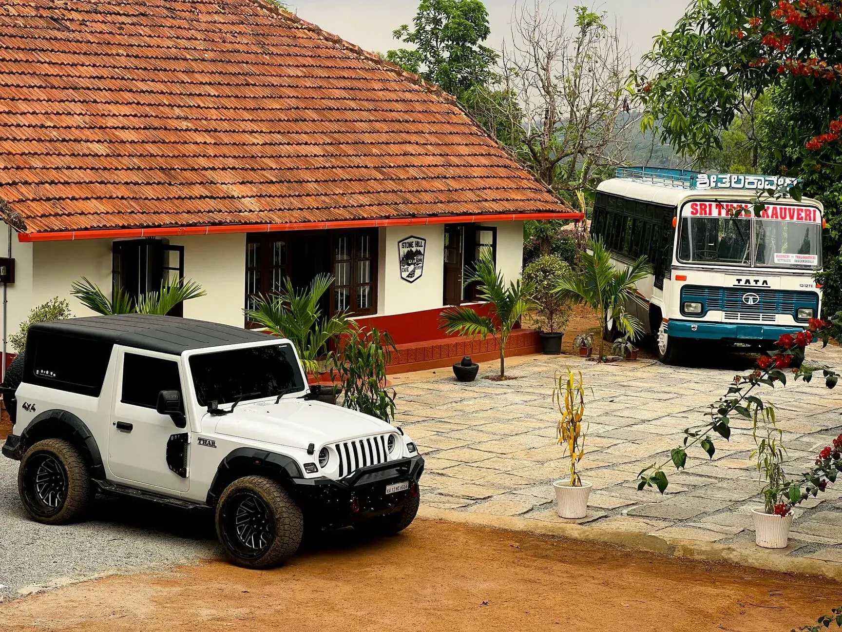 The Stone Hill house with its long tiled roof, a jeep and the bus in the paved courtyard.