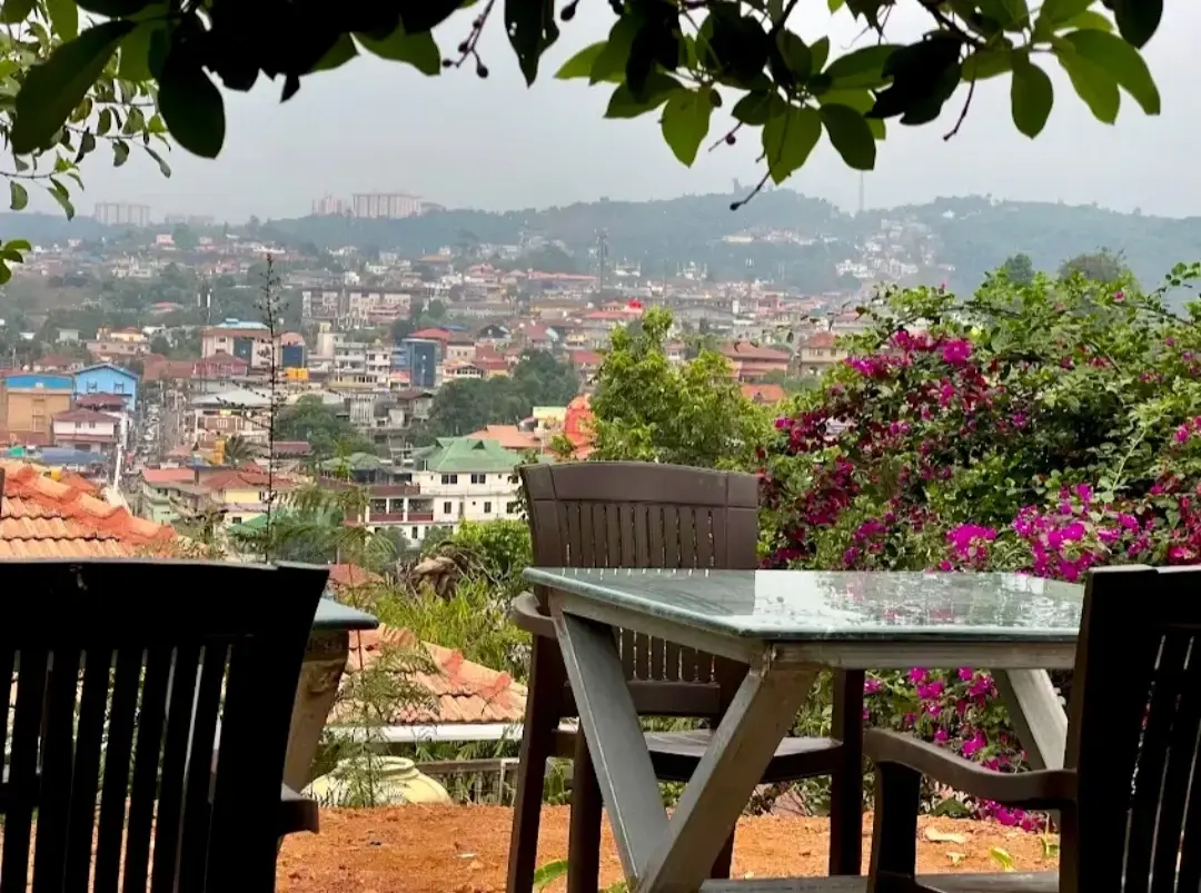 A wooden table on the terrace under bougainvillea, looking out over the rooftops of Madikeri.